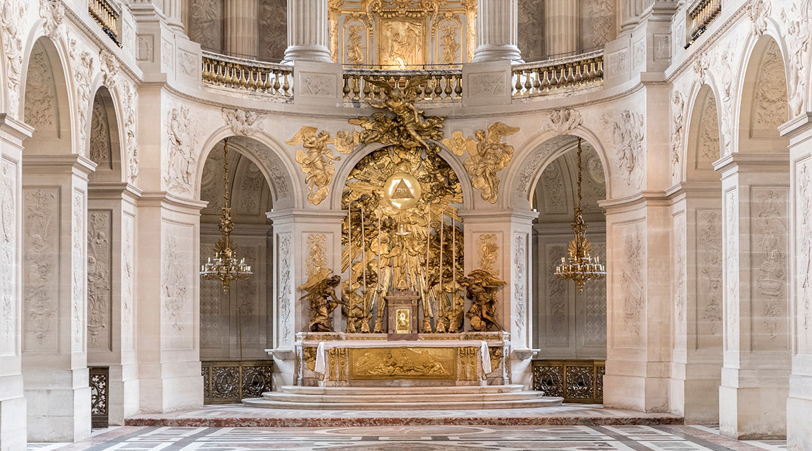 A gold altar in a church or cathedral with marble floor and arches