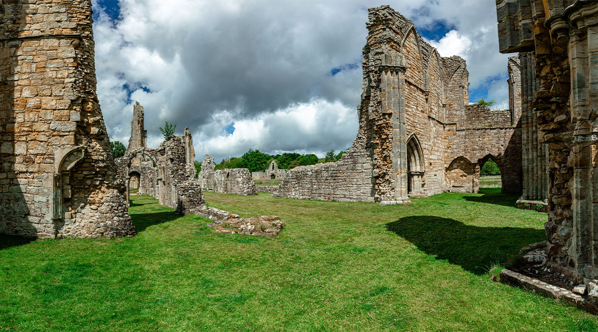 Ruïnes van middeleeuwse abdij tegen achtergrond van onstuimige wolken