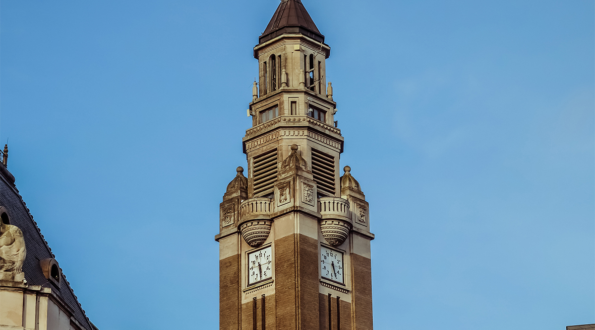 Top of a belfry with a modern clock on two sides of the tower