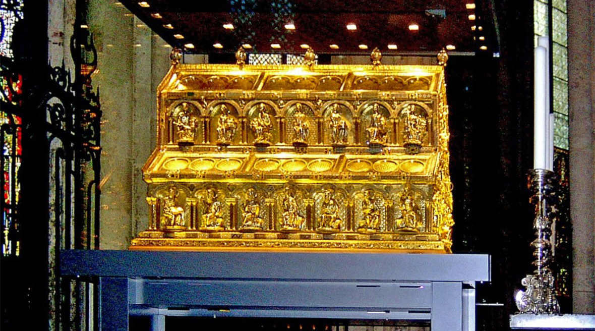 A gold sarcophagus in a glass display platform in a church or cathedral