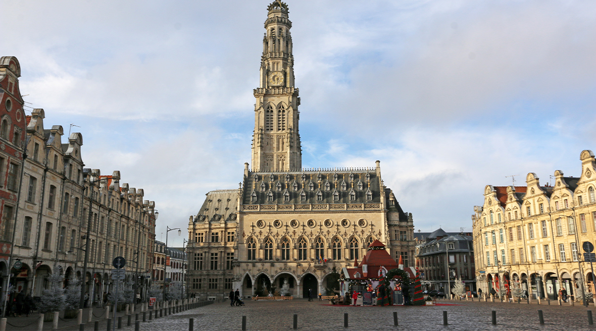 A tall tower and Renaissance style civic building with attractively gabled buildings either side of it on a large cobbled square
