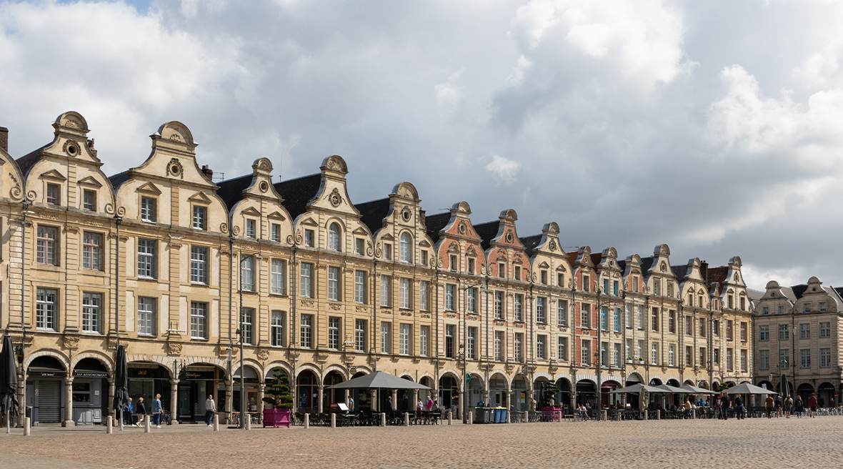 A row of attractive Dutch-style buildings with gables and arcades, on a large cobbled square