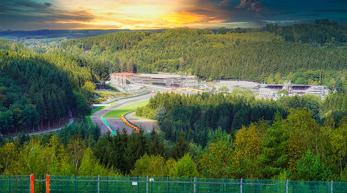 A motor racing circuit running through dense forest, with the sun about to set.