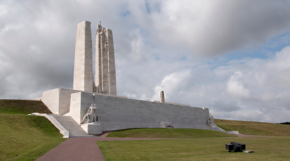 An imposing white war memorial stands on a raised area of land