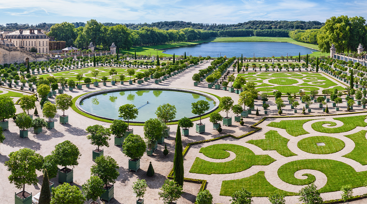 An immaculate and ornate garden with a round pond at a royal palace