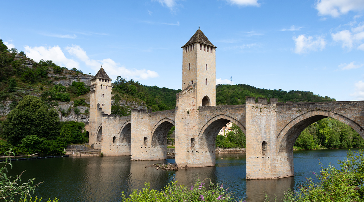 A medieval bridge across a river with two towers and five arches visible