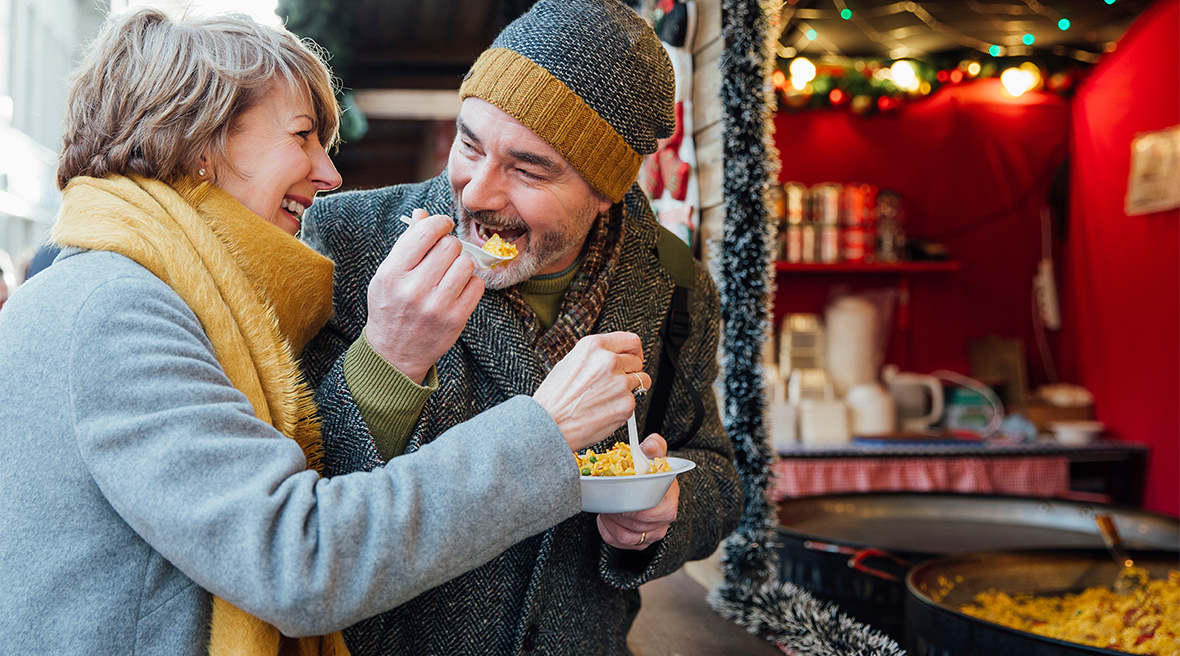 Een man en een vrouw genieten van de lekkernijen op de kerstmarkt van Newcastle