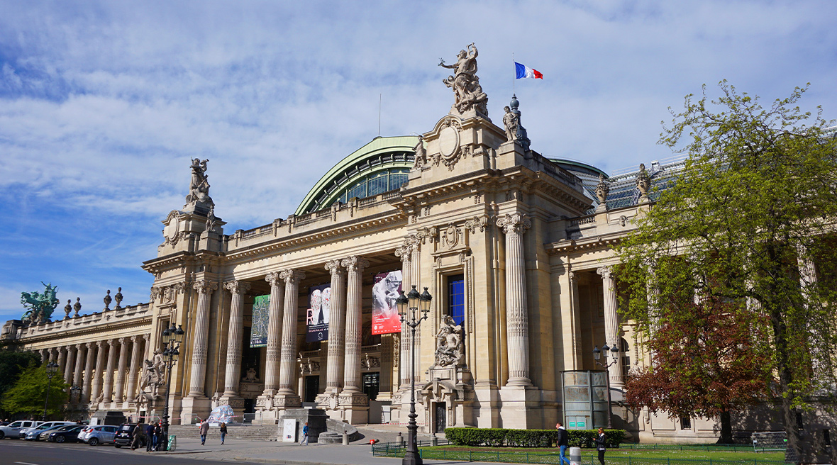 Neo-classical gallery or museum building on a wide city street with a French flag flying