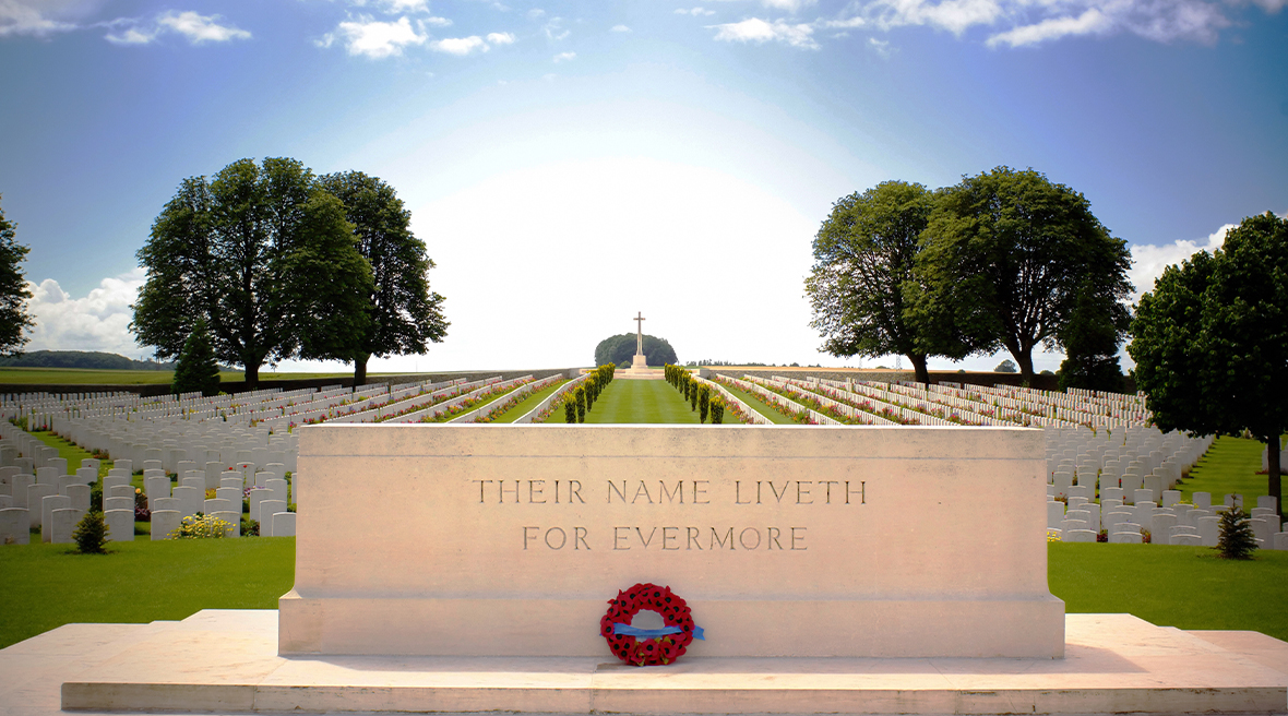 A Commonwealth cemetery on a beautiful summer’s day, foreground of a monumental inscription and poppy wreath